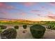 Breathtaking view of the golf course, lake and desert mountains with pink and purple sky at 8139 E Club Village Dr, Gold Canyon, AZ 85118