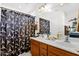 Bathroom with a double sink vanity, framed mirror, and a shower with black and white pattern curtain at 8429 W Vernon Ave, Phoenix, AZ 85037