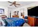 Bedroom with a blue quilt on the bed, a ceiling fan, and a wooden dresser with mirror and decor at 8429 W Vernon Ave, Phoenix, AZ 85037