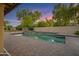 Inviting backyard with a refreshing pool, brick patio, rock waterfall feature, and mature trees at 9 E Los Arboles Cir, Tempe, AZ 85284