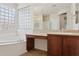 Bright bathroom featuring a soaking tub with glass block window and a vanity with dark wood cabinets at 11142 E Ravenna Ave, Mesa, AZ 85212