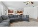 Open-concept living room features a large gray sectional sofa, plush rug, and seamless flow to the kitchen area at 11142 E Ravenna Ave, Mesa, AZ 85212