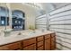 Well-lit bathroom with a double sink vanity, decorative mirror, neutral walls, and a bathtub-shower with curtain at 1482 S Banning St, Gilbert, AZ 85296