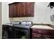 Functional laundry room with washer, dryer, utility sink, and dark wood cabinetry at 15407 W Windrose Dr, Surprise, AZ 85379