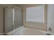 Bright bathroom features a glass shower enclosure and tub under a window with blinds at 15905 W Saguaro Ln, Surprise, AZ 85374