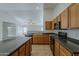 Modern kitchen with tile flooring, wooden cabinets, black appliances and granite countertops at 15905 W Saguaro Ln, Surprise, AZ 85374