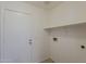 Functional laundry area with shelving, tile floor and exterior door access at 15905 W Saguaro Ln, Surprise, AZ 85374