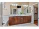 Bathroom featuring a double vanity, large mirrors, and walk-in closet access at 18045 W Rimrock St, Surprise, AZ 85388