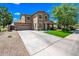 Beautiful two-story home featuring a two-car garage, well-manicured lawn, and a charming stone-accented entryway at 18045 W Rimrock St, Surprise, AZ 85388