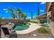 Backyard pool surrounded by rocks, palm trees, and a covered patio with stylish outdoor furniture at 18045 W Rimrock St, Surprise, AZ 85388
