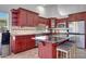 Well-equipped kitchen with cherry cabinets, black countertops, tile backsplash, and seating at the island at 23638 N 41St Ave, Glendale, AZ 85310