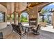 An inviting covered patio features stone columns, a fireplace, and comfortable seating arrangements at 2371 E Sanoque Ct, Gilbert, AZ 85298