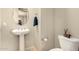 Clean and modern half bathroom with a pedestal sink, round mirror, and a toilet at 2554 E Honeysuckle Pl, Chandler, AZ 85286