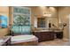 Bathroom featuring a soaking tub, large window, granite countertops, and dark wood cabinetry at 36813 N 109Th Way, Scottsdale, AZ 85262