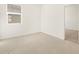 The bright bedroom has neutral tile flooring, a window, and leads into the hallway at 37168 W Prado St, Maricopa, AZ 85138