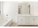 A clean, well-lit bathroom features a large mirror, white cabinets, and a tub at 37174 W La Paz St, Maricopa, AZ 85138