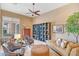 Comfortable living room with a ceiling fan, bookshelves, upholstered chairs, and a tufted ottoman at 41819 N Anthem Ridge Dr, Phoenix, AZ 85086
