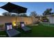 Inviting backyard with lounge chairs, putting green, wood fence, and covered hot tub, perfect for relaxation and entertainment at 4714 N Miller Rd, Scottsdale, AZ 85251