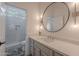 Bright bathroom features walk-in shower, a large round mirror and vanity with modern fixtures at 6069 E Ironwood Dr, Scottsdale, AZ 85266