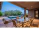Covered patio with dining table overlooking a pool with desert landscaping in the background at 6069 E Ironwood Dr, Scottsdale, AZ 85266