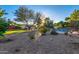 Expansive desert-landscaped backyard with desert foliage, mature shade trees, a pool and a synthetic lawn at 6615 E Desert Cove Ave, Scottsdale, AZ 85254