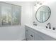 Bathroom with dual vanity, round mirror, modern fixtures, and window at 6615 E Desert Cove Ave, Scottsdale, AZ 85254