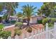 Well maintained front yard featuring mature palm and shade trees and desert landscaping behind a white picket fence at 8637 E Solano Dr, Scottsdale, AZ 85250