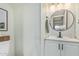 Clean half bath featuring modern fixtures, a round mirror, and neutral color scheme at 9050 N 51St Ln, Glendale, AZ 85302