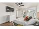 Bright bedroom featuring wood-look floors, ceiling fan, TV, and en-suite bathroom access at 9050 N 51St Ln, Glendale, AZ 85302