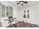 Bedroom featuring wood-look floors, a ceiling fan, a window, and musical instruments at 9050 N 51St Ln, Glendale, AZ 85302