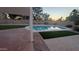 Beautiful backyard pool with stone surround, artificial turf, and a covered patio area, perfect for outdoor entertaining at 1044 N Arvada N --, Mesa, AZ 85205
