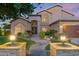 Elegant home exterior with arched windows, walkway, lush landscaping, and a two-car garage at dusk at 1073 N Layman St, Gilbert, AZ 85233