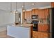 Spacious kitchen with wood cabinets, granite countertops, stainless steel appliances, and pendant lighting at 1114 S 220Th Ave, Buckeye, AZ 85326