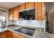A kitchen with wooden cabinets, a modern cooktop, and a view of an adjoining room at 1186 E Brenda Dr, Casa Grande, AZ 85122