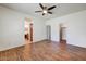 Spacious primary bedroom featuring wood-look floors and a ceiling fan, with bathroom and closet access at 12775 W Lowden Rd, Peoria, AZ 85383