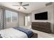 Bedroom featuring a ceiling fan, large window, and a dresser with wall-mounted television at 13153 W Cottontail Ln, Peoria, AZ 85383