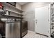 Modern laundry room equipped with stainless steel washer and dryer, accompanied by convenient shelving at 13153 W Cottontail Ln, Peoria, AZ 85383