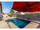 Backyard pool area with a red umbrella, palm trees, and privacy wall, perfect for relaxation and entertainment at 13153 W Cottontail Ln, Peoria, AZ 85383