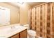 Neutral-toned bathroom featuring a vanity with a white sink, toilet, and patterned shower curtain at 15211 N 89Th Ave, Peoria, AZ 85381