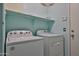 Bright laundry room featuring a white Whirlpool washer and dryer set, plus storage shelf at 16242 W Caribbean Ln, Surprise, AZ 85379