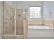 Bright bathroom featuring a tiled walk-in shower and separate soaking tub with a decorative glass block window at 18108 W Thunderhill Pl, Goodyear, AZ 85338