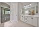 Well-lit bathroom with double vanity, framed mirrors and a glimpse into an adjacent bedroom at 18108 W Thunderhill Pl, Goodyear, AZ 85338