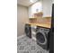 Modern laundry room featuring a black washer and dryer, white cabinetry, butcher block countertops, and a patterned tile floor at 1849 S 96Th St, Mesa, AZ 85209