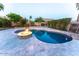 Outdoor oasis featuring a sparkling pool with a central fire pit surrounded by a paver patio and green landscaping at 1849 S 96Th St, Mesa, AZ 85209