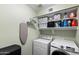 Well-organized laundry room with modern washer and dryer, shelving, storage, and an ironing board at 2111 E Rawhide St, Gilbert, AZ 85296