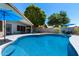 Backyard pool with lounge area, covered patio with dining set, lush landscaping, and privacy fence at 2111 E Rawhide St, Gilbert, AZ 85296