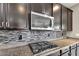 Close-up view of the kitchen, highlighting stainless steel appliances, mosaic backsplash, and granite countertops at 2264 W Arroyo Way, San Tan Valley, AZ 85144