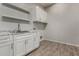 Laundry room featuring white cabinets, granite countertop, large sink, and wood-style flooring at 22944 E Via Del Oro --, Queen Creek, AZ 85142