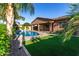 Backyard with sparkling blue pool, palm trees, synthetic grass, and covered patio at 22944 E Via Del Oro --, Queen Creek, AZ 85142