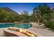 Resort-style backyard featuring a pool, spa, tanning ledge, fire features, lush landscaping, and mountain views at 26036 N 85Th Dr, Peoria, AZ 85383